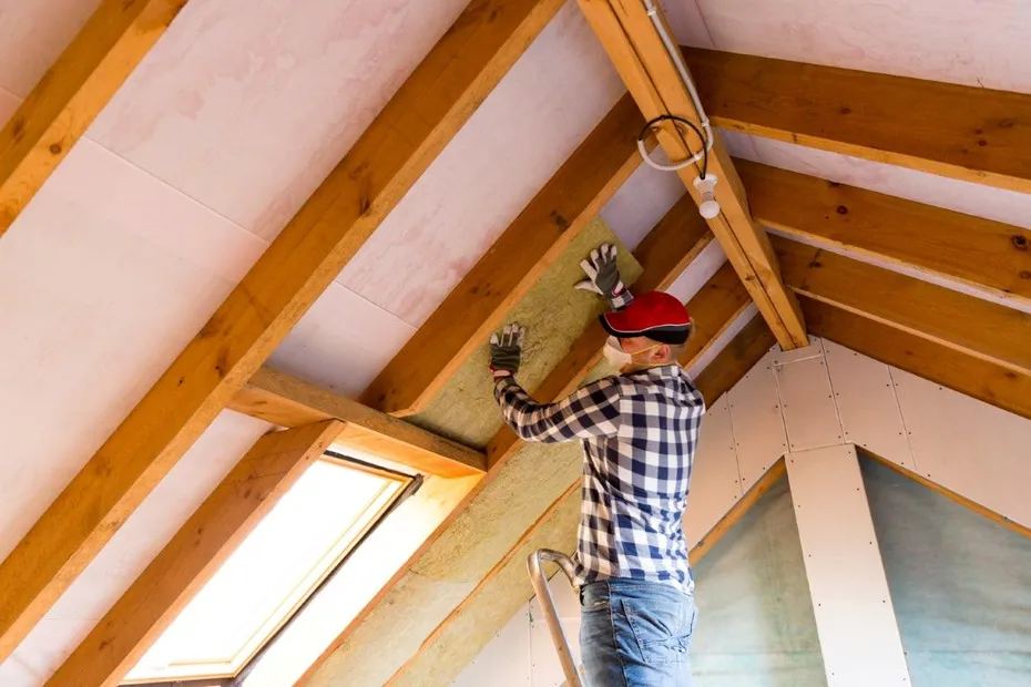 Installer fitting batt insulation along attic rafters