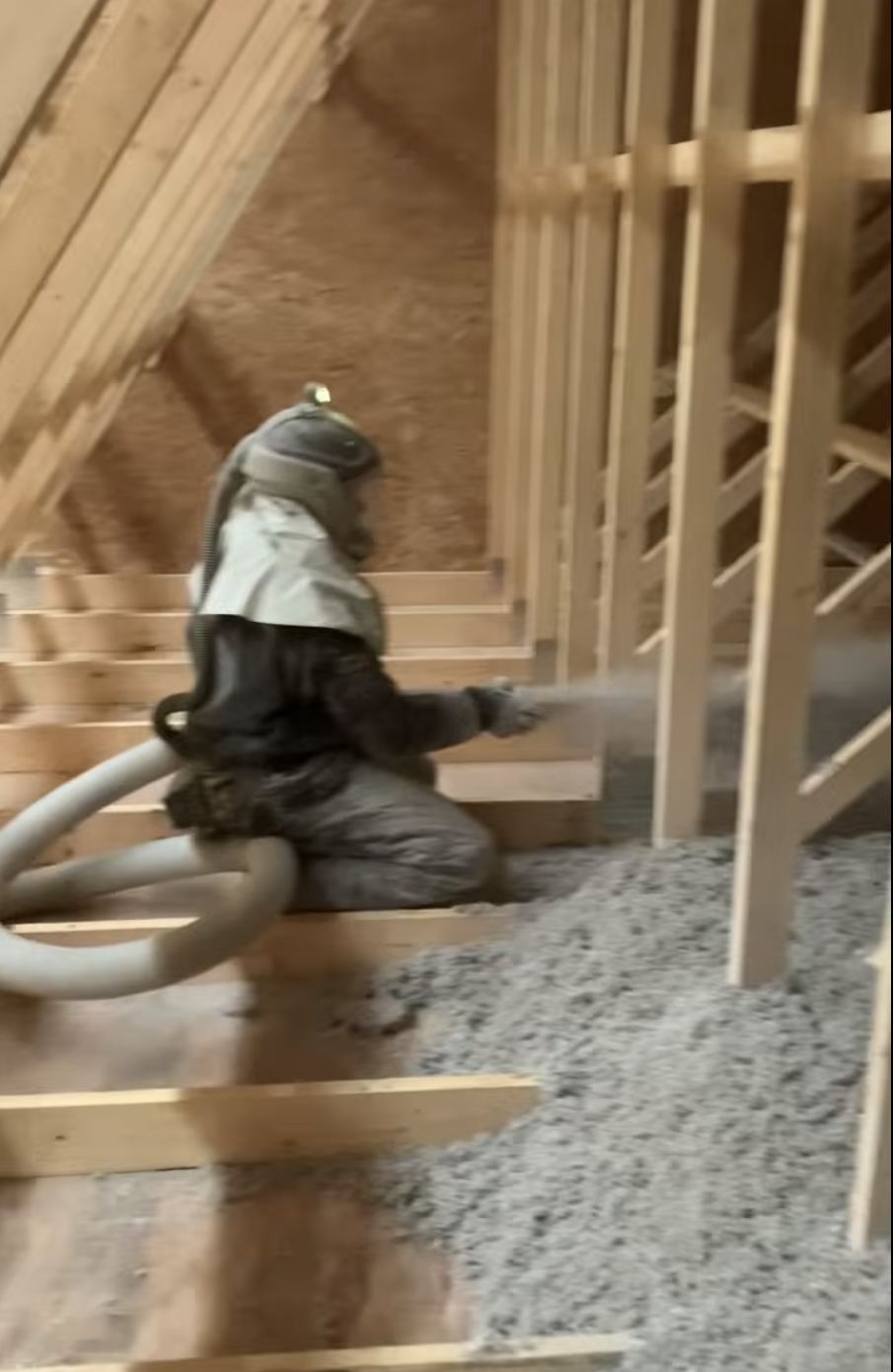 Installer blowing loose-fill insulation between exposed framing