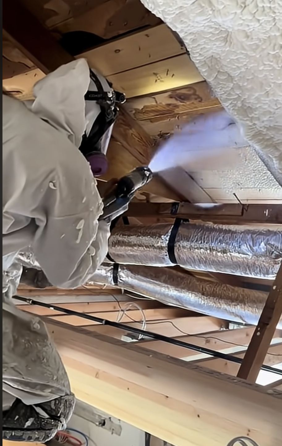 Installer spraying foam insulation onto the underside of a roof deck